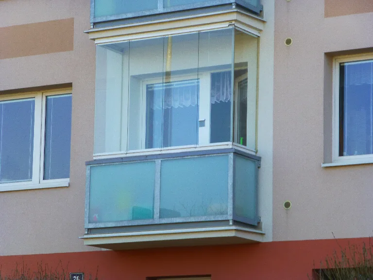 Krytý balkon bytového domu s kovovou konstrukcí a prosklením